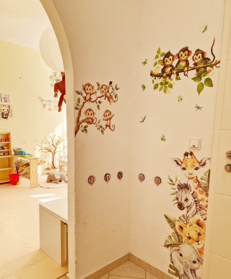 Wanddekoration mit Tiermotiven und Pflanzen in einem hellen Raum.