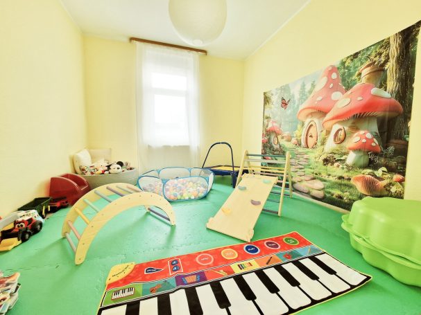 Bunte Spielzeuglandschaft mit Musikspielboden und Klettergerüst in einem kindgerechten Raum.